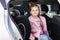 Handsome father put her daughter in a car seat and fastens her seat belts. Protection during the trip in the car.