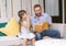 Handsome father sitting on sofa reading a story book to his daughter in the living room at home. Smiling single father caring