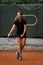 handsome female tennis player with racket and ball prepares to serve at beginning of game