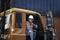 Handsome foreman worker wearing safety equipment, giving thumb up and smiling in truck at logistic shipping cargo containers yard