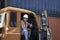 Handsome foreman worker wearing safety equipment, giving thumb up and smiling in truck at logistic shipping cargo containers yard