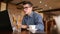 Handsome freelancer businessman in glasses diligently working on laptop in cafe and then drinks cup of coffee. Man