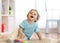 Handsome funny curly little boy sits on soft carpet in room and looks up