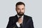 Handsome gentleman in business suit adjusting his tie against grey background