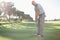 Handsome golfer putting ball on the green