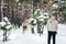 Handsome groom in beige pullover on background of blurred bride in snowy forest. Winter wedding. Artwork.