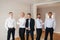 Handsome groom with his groomsman at home. Five man. Groom dressed in suit, gromsmen in white shirt. Funny guys on the