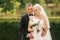 Handsome groom hug his beautiful bride. Newlyweds walking in the park. Blond hair woman in elegant wedding dress