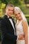 Handsome groom hug his beautiful bride. Newlyweds walking in the park. Blond hair woman in elegant wedding dress