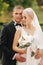 Handsome groom hug his beautiful bride. Newlyweds walking in the park. Blond hair woman in elegant wedding dress