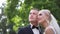 Handsome groom hug his beautiful bride. Newlyweds walking in the park. Blond hair woman in elegant wedding dress