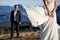 Handsome groom looking at his beatiful bride posing on foreground. Honeymoon in the mountains