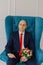 Handsome groom sits on a chair with a wedding bouquet.