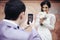 Handsome groom taking photo of beautiful bride on his phone