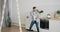 Handsome guy dancing in kitchen wearing headphones holding smartphone