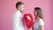 Handsome guy giving heart shape balloon to girl expressing love on valentine`s day