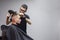 Handsome guy has a haircut in a barbershop, a Kazakh barber dries a client`s hair dryer against a gray wall, a hairdresser makes