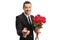 Handsome guy in a suit holding a bouquet of roses and a ring in a box