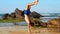 Handsome gymnast walks on hands along coastal wet sand