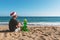 Handsome happy man in santa hat with inflatable Christmas tree on the beach. Christmas vacation concept