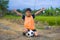 Handsome and happy young boy holding soccer ball playing football outdoors at green grass field smiling cheerful in training vest