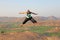 Handsome high jump man. A bald man wearing sunglasses in Hampi, jumps high on Anjaneya Hill, Hanuman Temple. Rice fields or