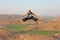 Handsome high jump man. A bald man wearing sunglasses in Hampi, jumps high on Anjaneya Hill, Hanuman Temple. Rice fields or