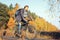 Handsome hipster man in casual wear with backpack riding bicycle in autumn park or forest. Discovery beautiful fall season