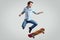 Handsome hipster man in jeans jacket doing the flip on stylish skateboard