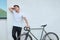 Handsome hipster man posing with bicycle in the city.