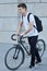 Handsome hipster man posing with bicycle in the city.