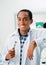 Handsome hispanic dentist wearing white doctors coat and holding dental tool while smiling posing to camera