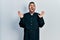 Handsome hispanic man with beard wearing catholic priest robe celebrating mad and crazy for success with arms raised and closed