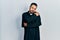 Handsome hispanic man with beard wearing catholic priest robe hugging oneself happy and positive, smiling confident