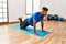 Handsome hispanic man doing exercise and stretching on yoga mat, practicing flexibility and training at the gym