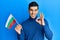 Handsome hispanic man holding bulgarian flag doing ok sign with fingers, smiling friendly gesturing excellent symbol