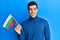 Handsome hispanic man holding bulgarian flag looking positive and happy standing and smiling with a confident smile showing teeth