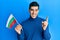 Handsome hispanic man holding bulgarian flag smiling happy pointing with hand and finger to the side