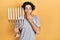 Handsome hispanic man holding menorah hanukkah jewish candle covering mouth with hand, shocked and afraid for mistake