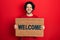 Handsome hispanic man holding welcome doormat smiling with a happy and cool smile on face