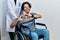 Handsome hispanic man sitting on wheelchair wearing neck collar smiling in love doing heart symbol shape with hands