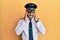 Handsome hispanic man wearing airplane pilot uniform with hand on head, headache because stress