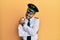 Handsome hispanic man wearing airplane pilot uniform hugging oneself happy and positive, smiling confident