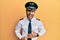 Handsome hispanic man wearing airplane pilot uniform smiling and laughing hard out loud because funny crazy joke with hands on