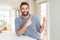 Handsome hispanic man wearing casual sweatshirt at home smiling and looking at the camera pointing with two hands and fingers to