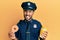 Handsome hispanic police man eating donut and drinking coffee winking looking at the camera with sexy expression, cheerful and