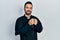 Handsome hispanic priest man with beard praying holding catholic rosary smiling with a happy and cool smile on face