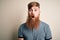 Handsome Irish redhead man with beard and arm tattoo standing over isolated background afraid and shocked with surprise