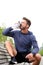 Handsome jogger sitting on bench drinking water