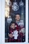 Handsome Kids standing by the decorated window with a toy santa claus and look and wait Christmas eve. Children hug and enjoy the